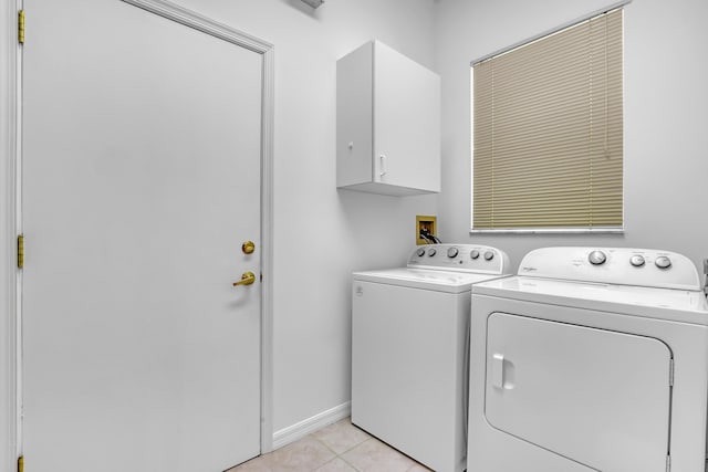 clothes washing area with light tile patterned floors, independent washer and dryer, cabinet space, and baseboards