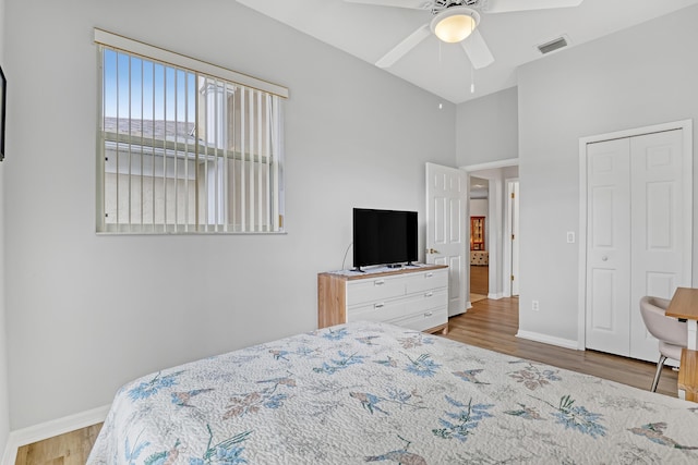 bedroom with a ceiling fan, visible vents, baseboards, and wood finished floors