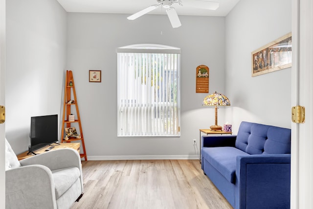 sitting room with a ceiling fan, light wood-style flooring, and baseboards