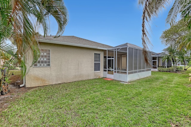 rear view of property with glass enclosure and a lawn