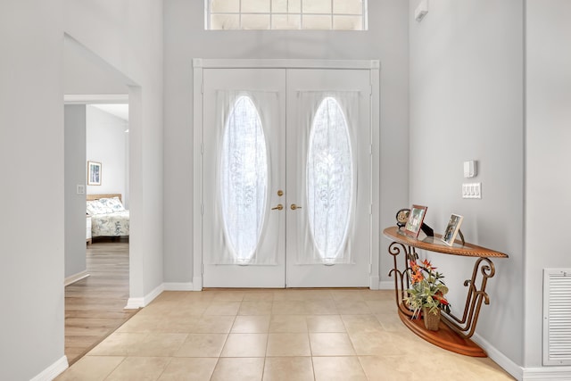 foyer entrance with light tile patterned flooring, baseboards, visible vents, and french doors