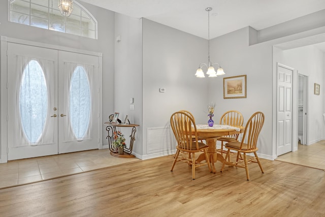 entrance foyer featuring an inviting chandelier, french doors, and light hardwood / wood-style flooring