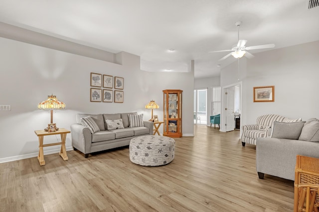 living area with baseboards, ceiling fan, visible vents, and light wood finished floors