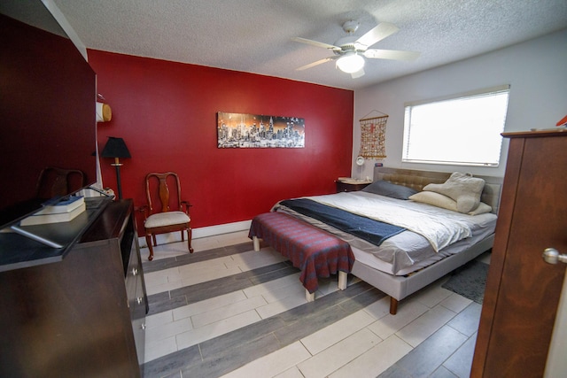 bedroom featuring ceiling fan, light hardwood / wood-style floors, and a textured ceiling