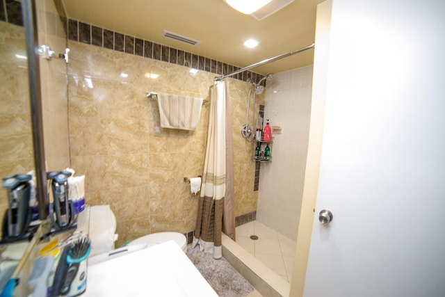 bathroom with toilet, curtained shower, and tile walls