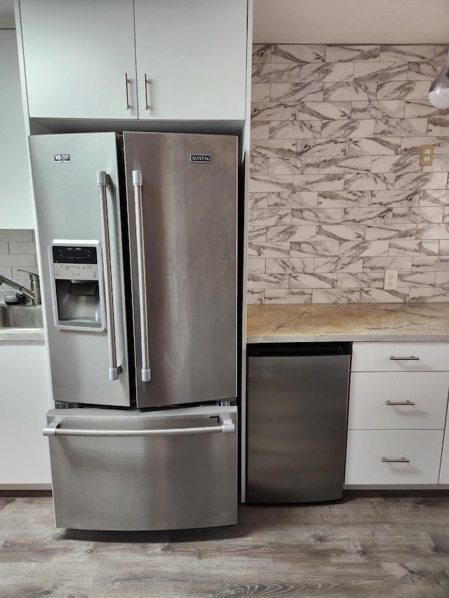 kitchen with white cabinetry, stainless steel fridge with ice dispenser, sink, and light hardwood / wood-style flooring