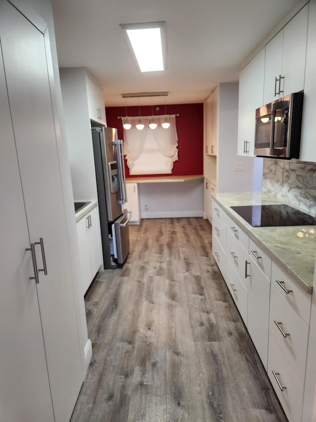 kitchen with white cabinets, decorative light fixtures, appliances with stainless steel finishes, and light hardwood / wood-style flooring