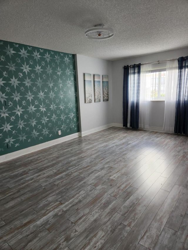 empty room featuring wood-type flooring and a textured ceiling