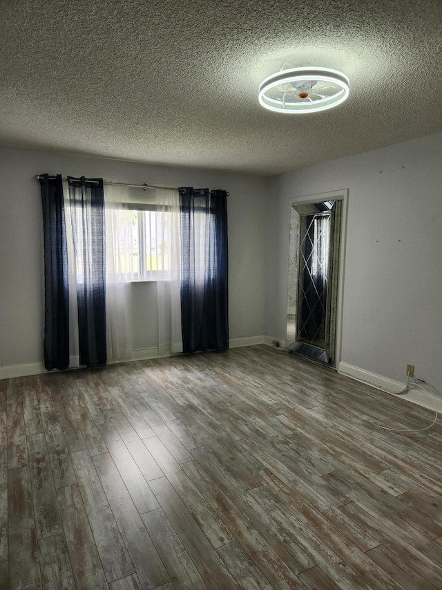 empty room with hardwood / wood-style floors and a textured ceiling