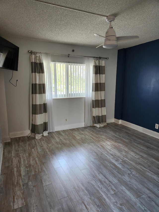 empty room featuring ceiling fan, wood-type flooring, and a textured ceiling