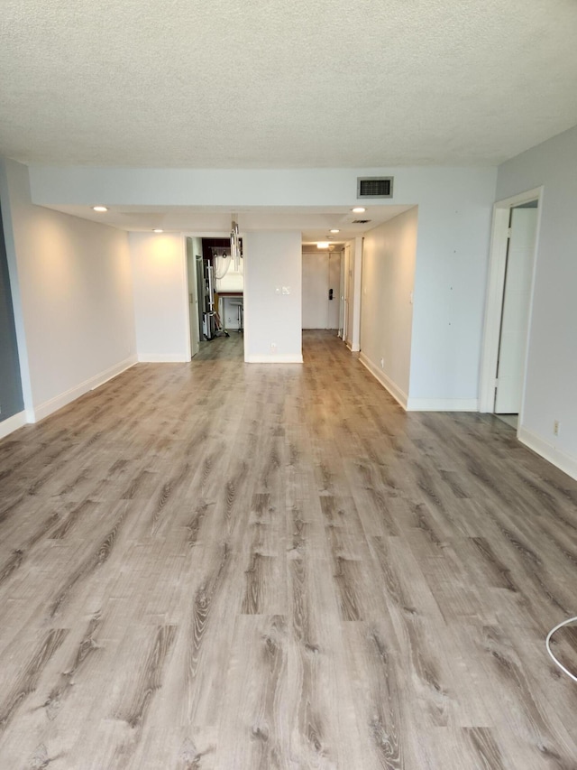 unfurnished living room featuring light hardwood / wood-style floors and a textured ceiling