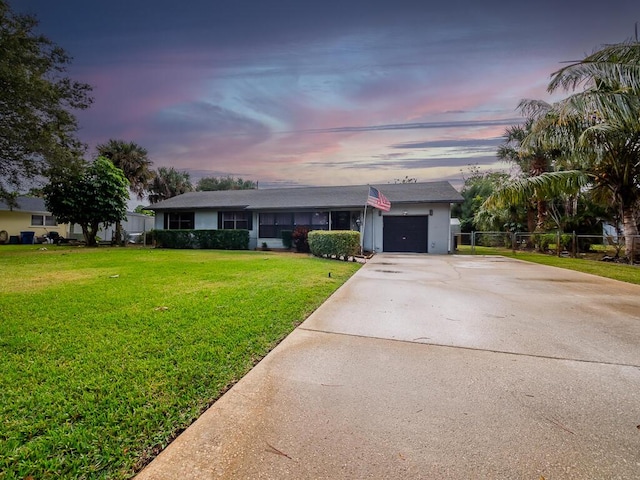 single story home featuring a lawn and a garage