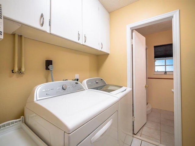 laundry room featuring washer and clothes dryer, light tile patterned flooring, and cabinets