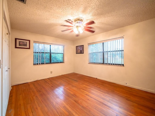 spare room with ceiling fan, a textured ceiling, and hardwood / wood-style flooring