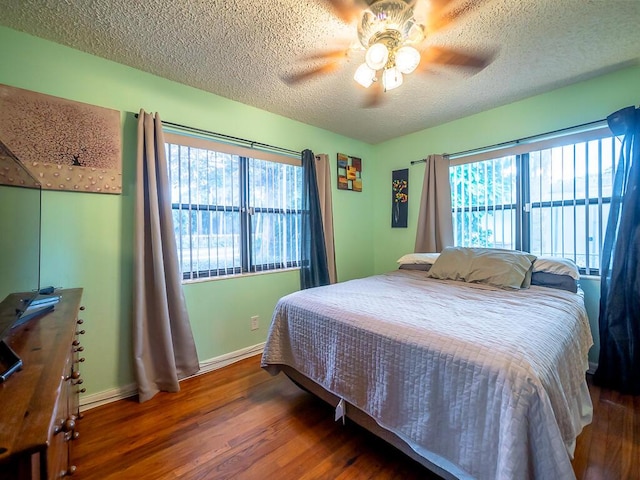 bedroom with a textured ceiling, dark hardwood / wood-style floors, and ceiling fan