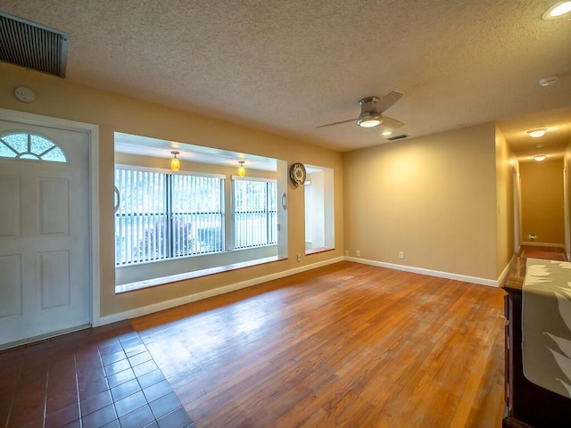 unfurnished living room with ceiling fan, a healthy amount of sunlight, a textured ceiling, and hardwood / wood-style flooring