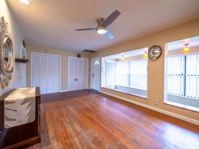 unfurnished living room featuring hardwood / wood-style flooring, ceiling fan, and a textured ceiling