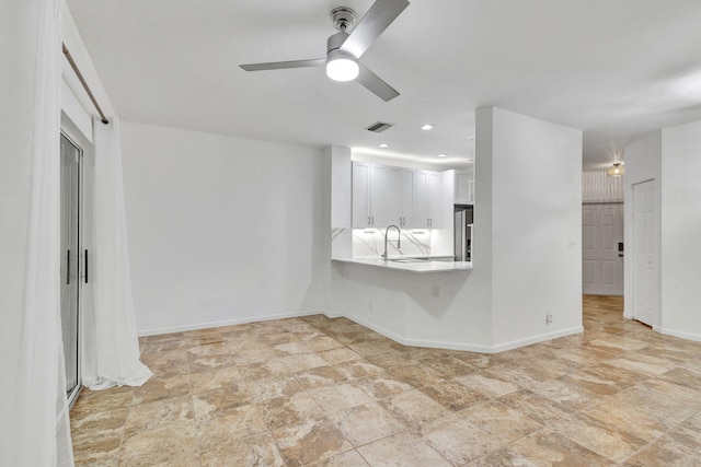 unfurnished living room with ceiling fan and sink