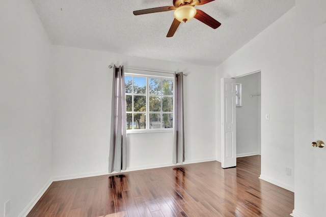 empty room with lofted ceiling, ceiling fan, hardwood / wood-style floors, and a textured ceiling