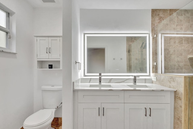 bathroom featuring vanity, toilet, and a shower with door