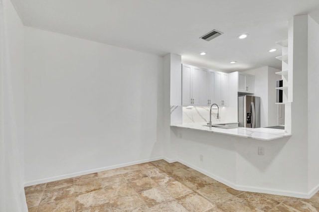 kitchen featuring white cabinets, sink, kitchen peninsula, and stainless steel refrigerator with ice dispenser