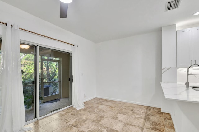 unfurnished dining area featuring ceiling fan and sink