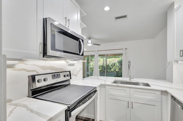 kitchen with light stone counters, sink, white cabinetry, and stainless steel appliances