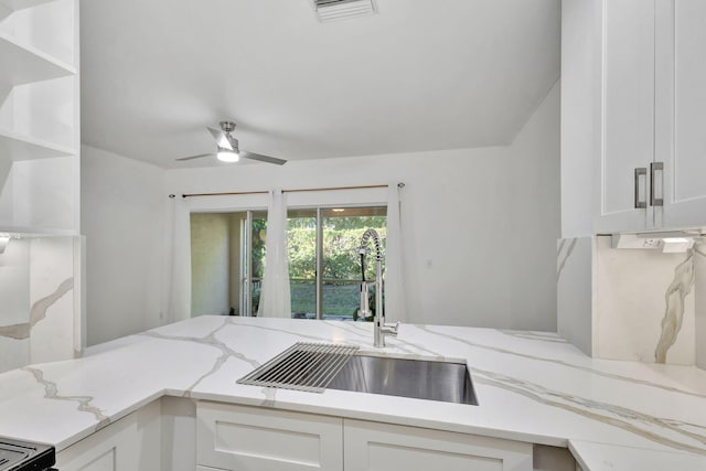 kitchen featuring light stone countertops, white cabinetry, ceiling fan, and sink