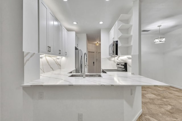 kitchen featuring kitchen peninsula, sink, appliances with stainless steel finishes, decorative light fixtures, and white cabinetry