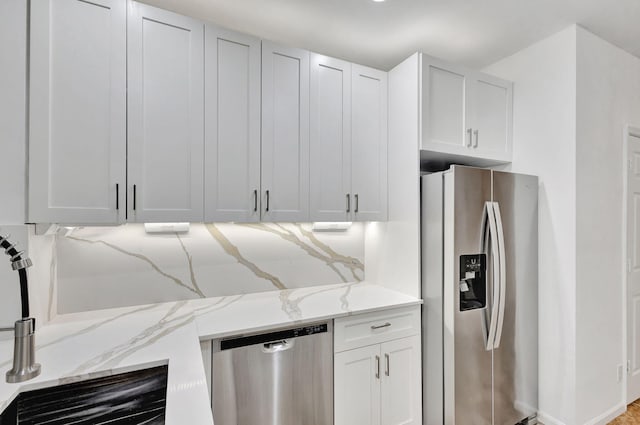 kitchen with white cabinets, appliances with stainless steel finishes, and light stone counters