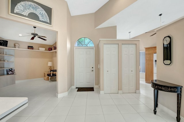 tiled foyer entrance with ceiling fan and a towering ceiling