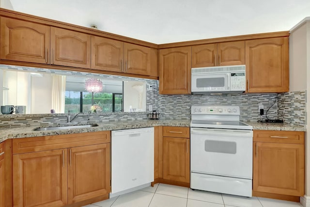 kitchen featuring sink, white appliances, and light stone countertops