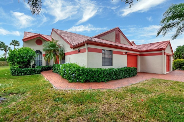 view of front of house featuring an attached garage, a front yard, stucco siding, and driveway