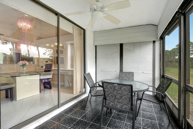 sunroom with ceiling fan with notable chandelier