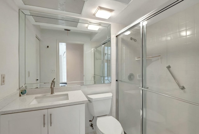 bathroom featuring a shower with door, toilet, and vanity