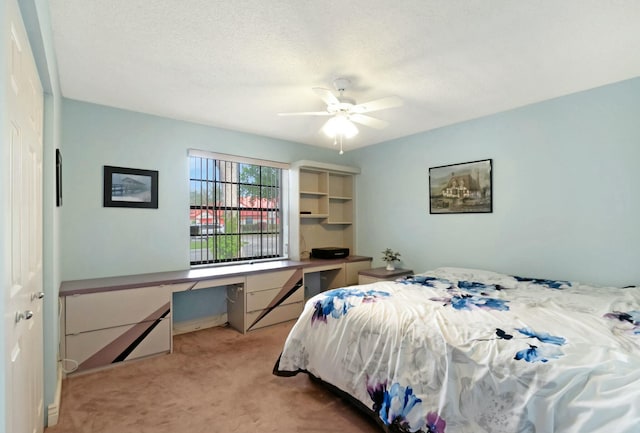 carpeted bedroom featuring ceiling fan and built in desk