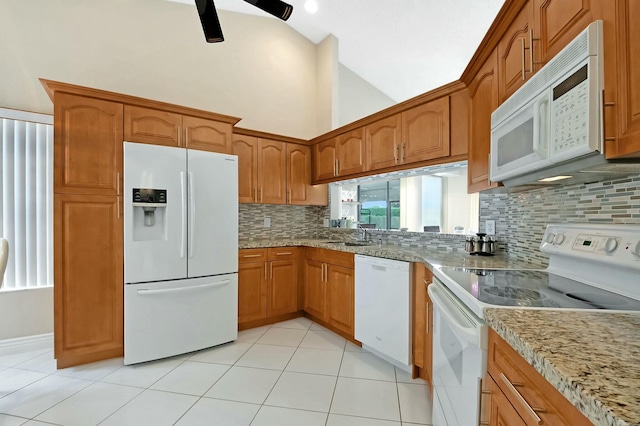 kitchen with tasteful backsplash, light tile patterned floors, light stone counters, and white appliances