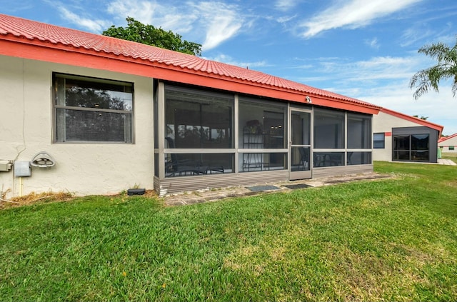 rear view of house with a sunroom and a lawn