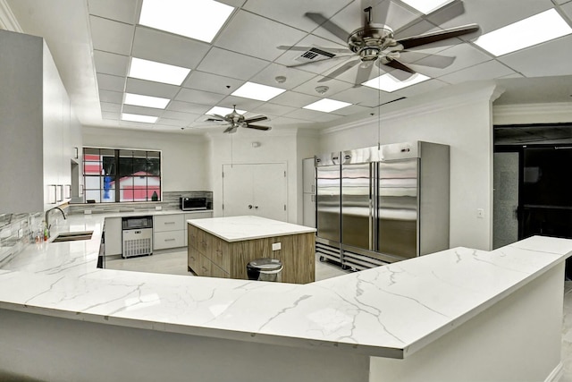 7676 Lexington Club Blvd Unit A, Delray Beach, FL 33446 - kitchen with a ceiling fan, a sink, built in refrigerator, light stone counters, and decorative backsplash