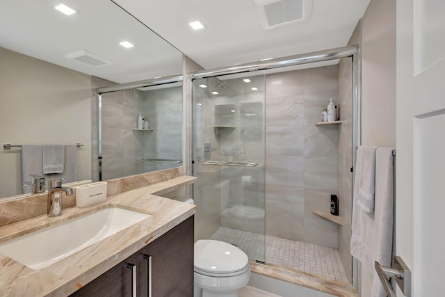 bathroom featuring a shower with door, vanity, and toilet