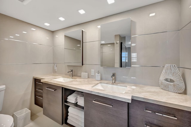 bathroom featuring tile walls, vanity, and toilet