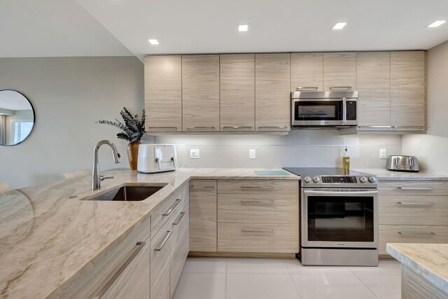 kitchen with light stone counters, a wall of windows, sink, and light brown cabinets