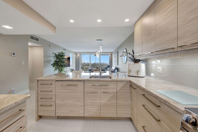 kitchen featuring light stone countertops, sink, light brown cabinetry, and kitchen peninsula