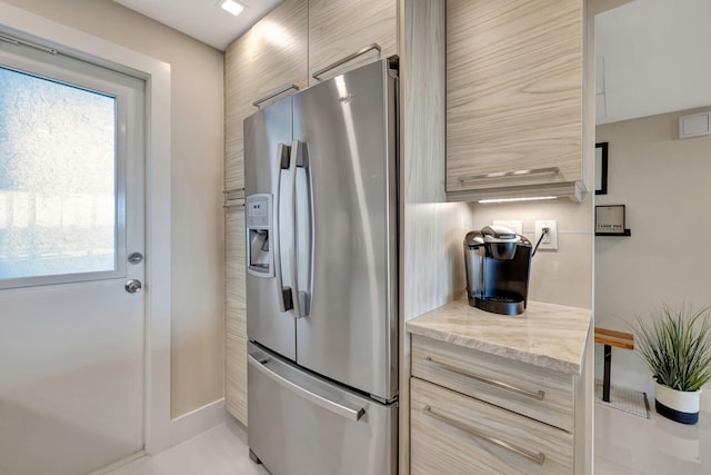 kitchen with light stone countertops, light brown cabinets, and stainless steel fridge with ice dispenser