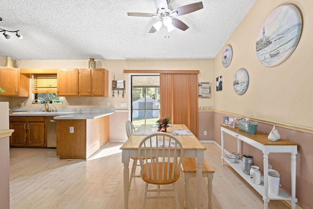 kitchen with sink, light hardwood / wood-style flooring, ceiling fan, a textured ceiling, and a kitchen island