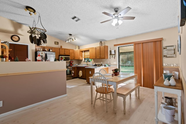 dining area with ceiling fan, light hardwood / wood-style floors, a textured ceiling, and vaulted ceiling