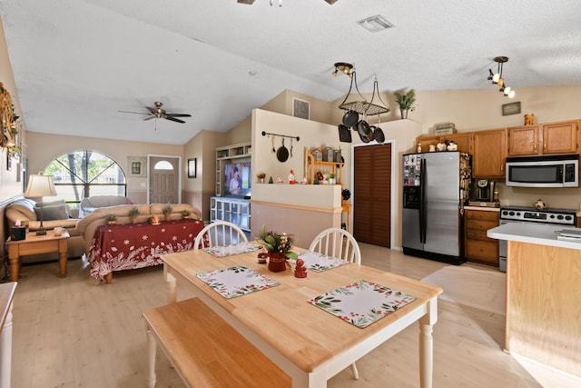 dining room featuring a textured ceiling, light wood-type flooring, vaulted ceiling, and ceiling fan