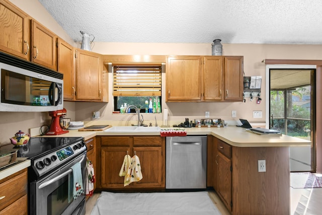 kitchen featuring kitchen peninsula, sink, a textured ceiling, and appliances with stainless steel finishes