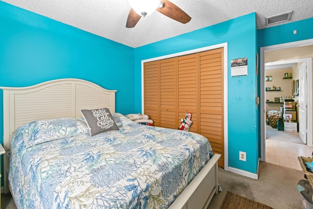 carpeted bedroom featuring a textured ceiling, a closet, and ceiling fan