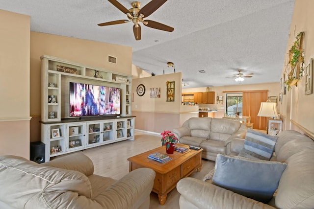 living room with ceiling fan, lofted ceiling, and a textured ceiling